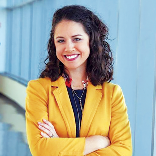Headshot of Dr. Marlo Cavnar in formal attire standing in a hallway.