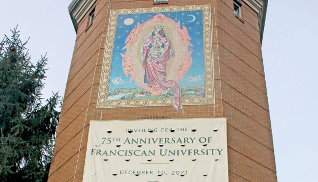 Building tower with mosaic of the Virgin Mary and a banner announcing the 75th anniversary of Franciscan University.