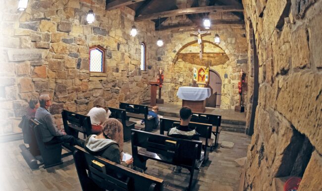 People pray in a stone chapel with the Eucharist exposed in the tabernacle.