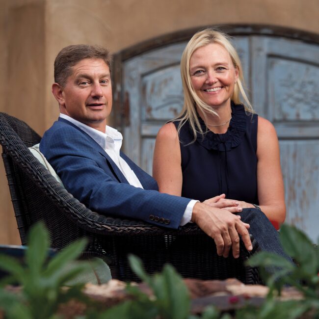 Man and woman in formal attire sitting in wicker chairs.
