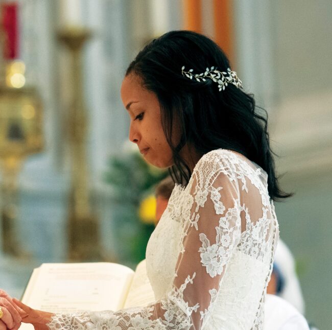 Woman in bridal-style attire kneeling at the altar in a church.