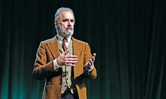 Dr. Jordan Peterson on stage talking and gesturing with his hands.