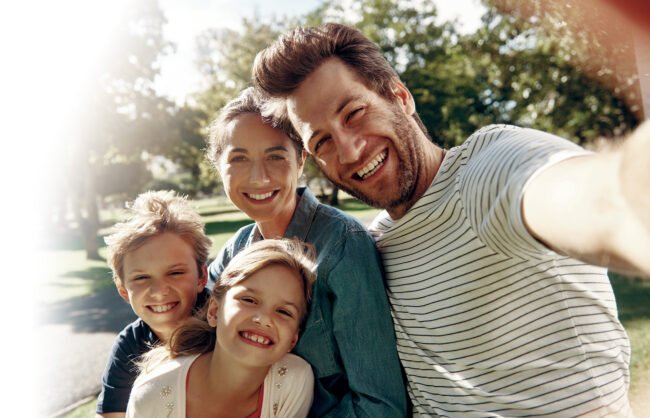 Selfie of a man and woman with a boy and a girl sitting outside.