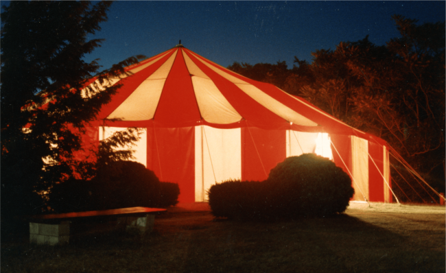 A large red and white tent in the night.