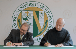 Dale Ahlquist, president of the Chesterton Schools Network, and University President Father Dave Pivonka,TOR, sign the partnership agreement on April 8.
