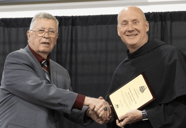 Coach Bob Kramer shaking hands with Fr. Dave Pivonka.