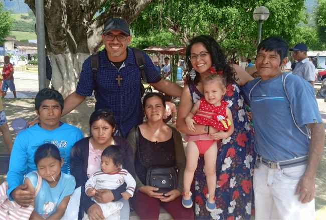 A family poses outside in front of a tree.