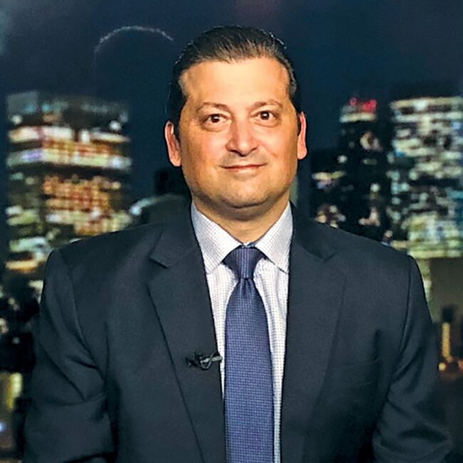 Jeff Cortese in a navy suit with a blurred city skyline behind him.