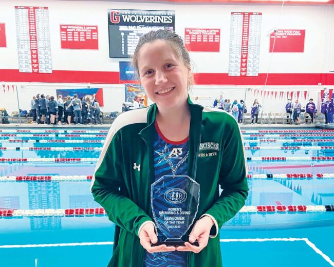 Katarina Antonov holding a swimming award in front of a pool.