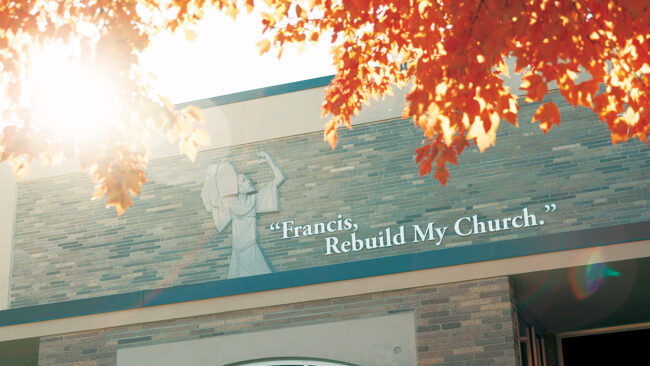 A building with an image of St. Francis with the text "Francis, Rebuild My Church" on the wall.