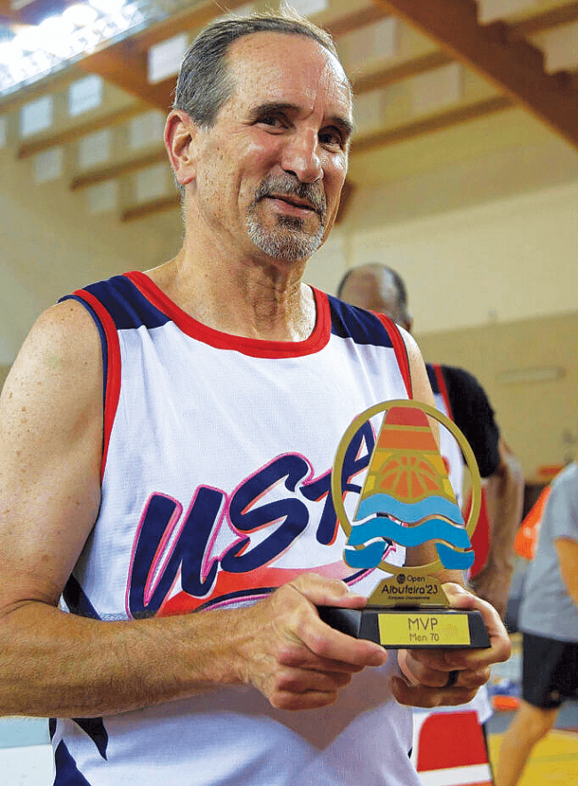 A man in a basketball uniform holding a trophy.