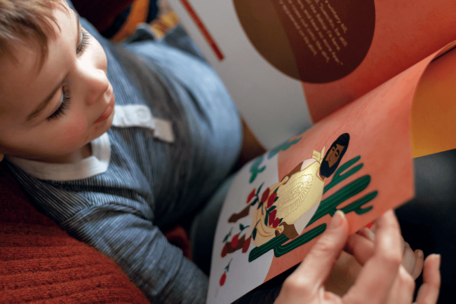 A child looking at a book with art of Juan Diego on the right hand page.