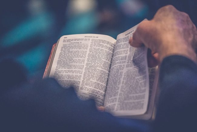 A hand turning the page of a bible.