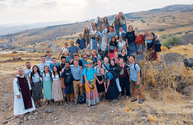 A group photo of students outside on a hill.