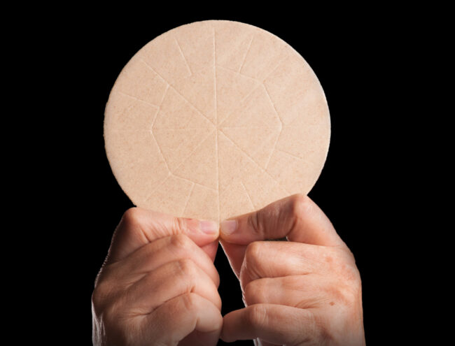 Two hands holding up the Eucharist.