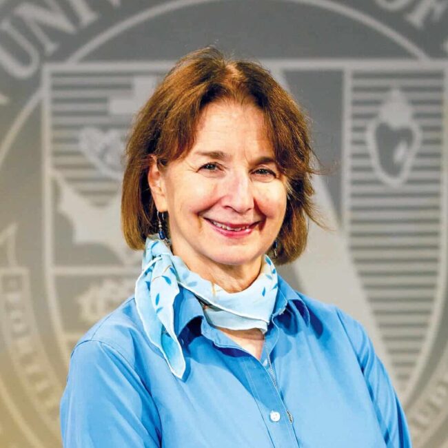 Dr. Marita O'Brien in a blue shirt in front of a university seal background.