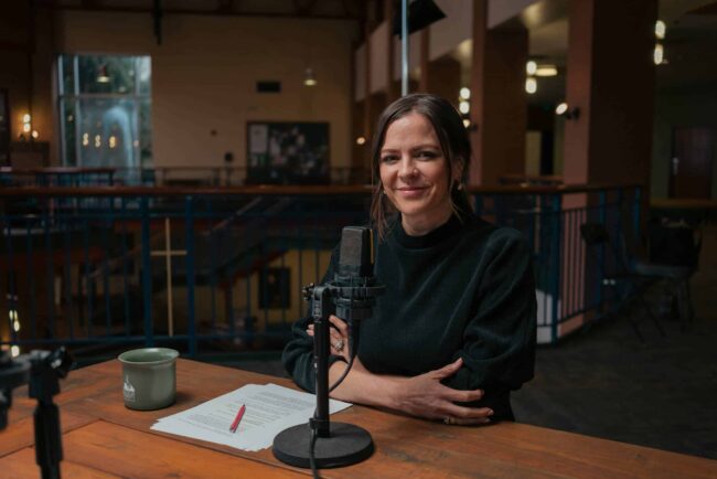 Noelle Mering sitting in front of microphone, smiling.