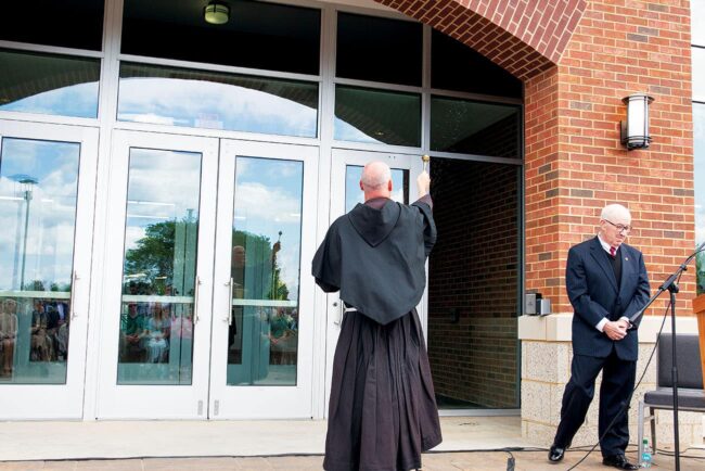 Fr. Dave sprinkles holy water on the main entrance to Christ the Teacher Hall.