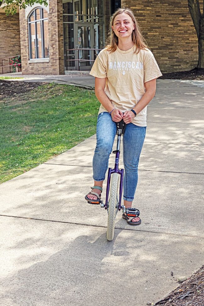 Madeline McKechnie in a yellow shirt and jeans sitting on a bike.