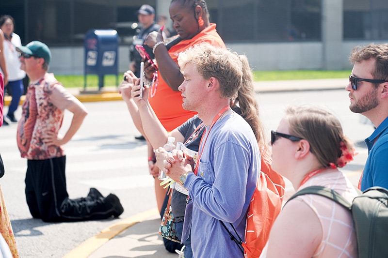 Young people kneel as the Eucharist is processed through downtown Indianapolis.