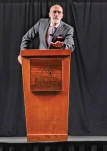 Dr. Arthur Brooks speaking at a podium with the Franciscan University of Steubenville.