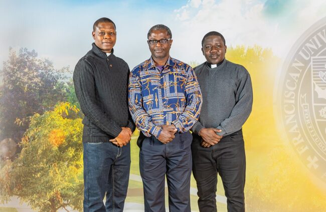 Fr. Sunday Yunana, Femi Adeojo, and Fr. John Ferdinand standing in front of an outside background.