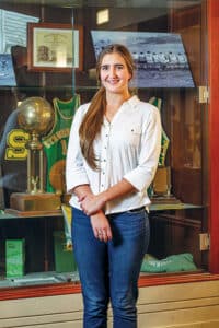 Maddie Doan standing in front of a sport's display case. 