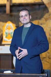 Taylor Bodoh, former Anglican priest, stands in a church pew. 