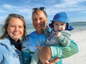 The Kuhlmans with their grandson standing on a beach.