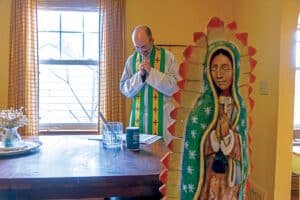 Father Jonathan St. André, TOR ’96, standing with an image of Our Lady of Guadalupe in the foreground. 