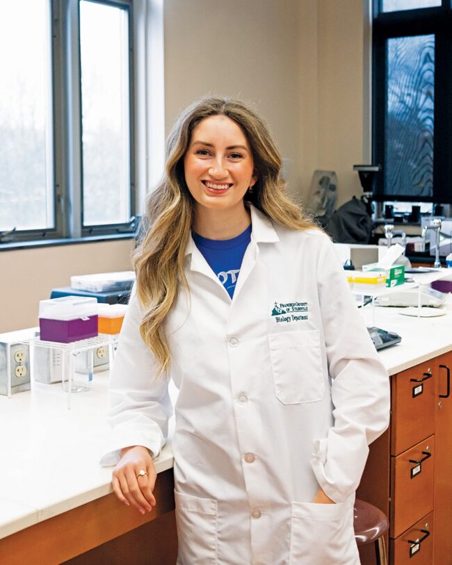 Rylie Severson in a lab coat standing in front of a counter.