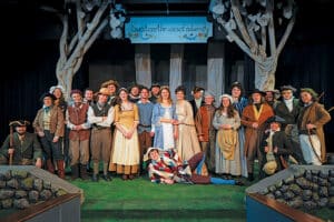 The cast of As You Like It on stage in Anathan Theatre standing in their costumes on a stage. 