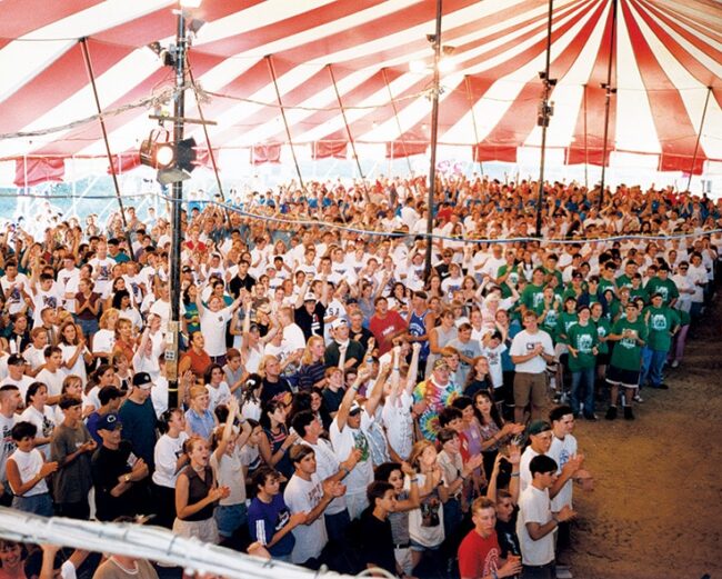 A group of people under a red and white tent.