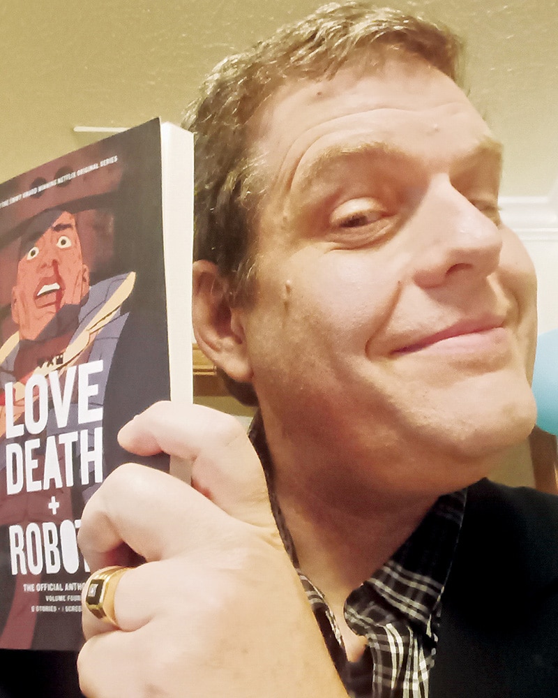 John (Coleman ’92) McNichol holding the anthology of the stories adapted for the fourth season of Love, Death, and Robots on Netflix