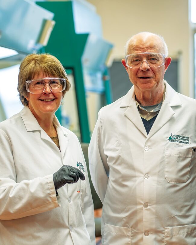 Sue and Bill Reighard in lab coats smiling at the camera.
