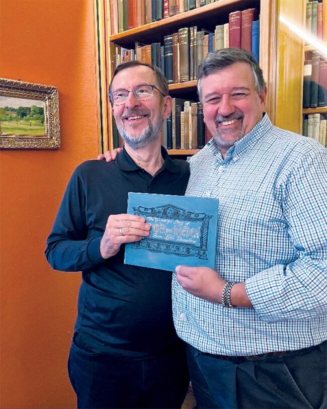Wolfgang Powischer and Thomas Costello standing in front of a bookcase.