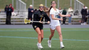 Franciscan University women’s lacrosse players competing during a game, with two athletes wearing goggles and battling for the ball on the field.