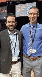 Crossroads 4 Christ co-founders Alex Soucy and Travis Moran wearing lanyards with two TV screens in the background.