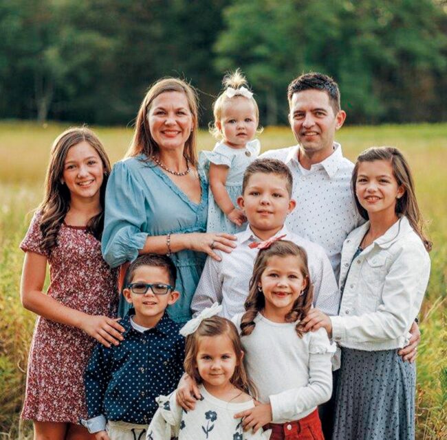 Outside family photo of two parents with their seven children.