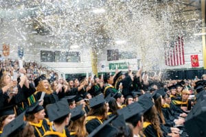Franciscan University Class of 2026 graduates celebrating at commencement with confetti falling in the arena.