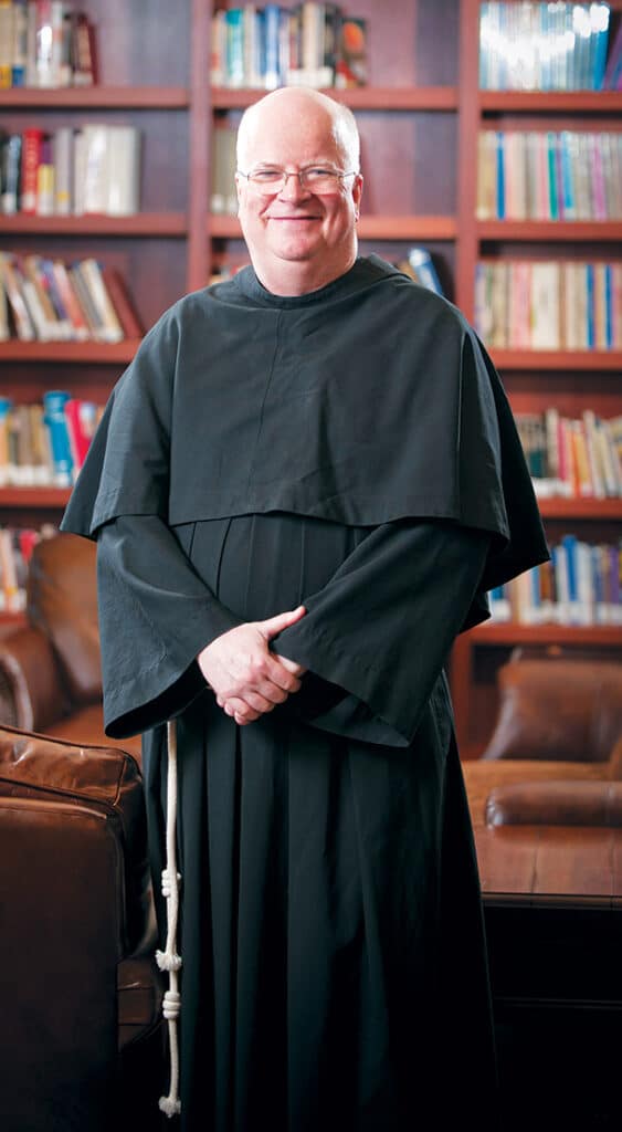 Portrait of Fr. Terence Henry, TOR standing in a library.