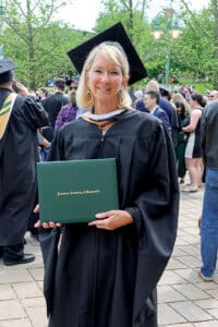 Katrina Zeno at Franciscan University of Steubenville graduation holding her diploma cover in academic regalia.