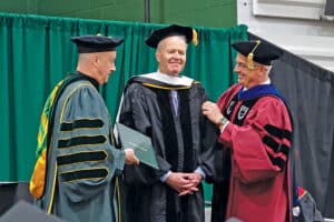 President Fr. Dave Pivonka, TOR, and Provost Dr. Stephen Hildebrand present Timothy Busch with an honorary diploma. 
