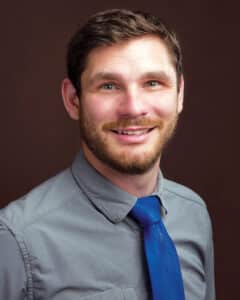 Professional headshot of Peter McCullough wearing a gray shirt and blue tie.